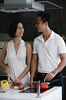 A couple prepare dinner together in the kitchen - Asia Images Group