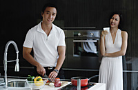 A couple prepare dinner together in the kitchen - Asia Images Group