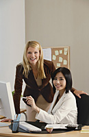 Two female colleagues smile at the camera together - Asia Images Group
