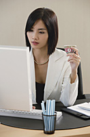 A woman drinks Chinese tea while she works - Asia Images Group