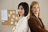 Two female colleagues look at the camera together - Asia Images Group