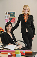 Two female colleagues smile at the camera together - Asia Images Group