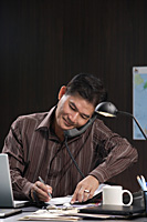 A man talks on the phone as he works - Asia Images Group