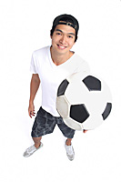 A man holds a soccerball and smiles at the camera - Asia Images Group