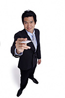 A man in a suit holds out his business card to the camera - Asia Images Group