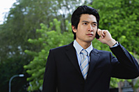 A man wearing a suit talks on his cellphone - Asia Images Group