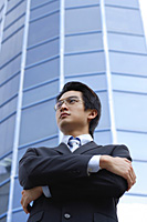 A man with a suit stands in front of a skyscraper - Asia Images Group