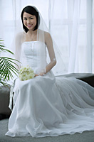 A bride with a white wedding gown sits down and smiles at the camera - Asia Images Group