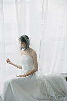 A bride with a white wedding gown sits down - Asia Images Group