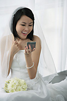 A bride does her makeup in the mirror - Asia Images Group