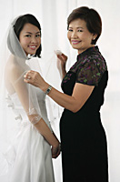 A bride and her mother smile at the camera together - Asia Images Group