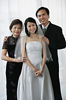 A bride and her family smile at the camera together - Asia Images Group