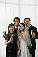 A newlywed couple and their family smile at the camera together - Asia Images Group