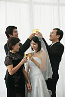 A newlywed couple and their family raise their glasses for a toast - Asia Images Group
