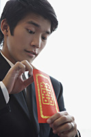 A groom looks inside a red envelope - Asia Images Group