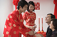 A groom offers a cup of tea to another family member - Asia Images Group