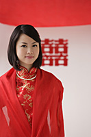 A bride wearing a red silk dress looks at the camera - Asia Images Group