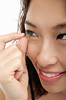 A young woman takes out her contact lens - Asia Images Group