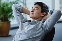 A man relaxes at his desk - Asia Images Group
