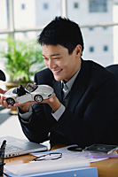 A man plays with a toy car on his desk - Asia Images Group
