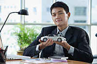 A man looks at the camera as he holds a toy car - Asia Images Group