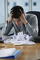A man looks stressed as he works at his desk - Asia Images Group