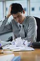 A man looks stressed as he works at his desk - Asia Images Group