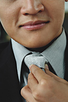 A man adjusts his tie - Asia Images Group