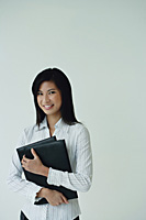 A businesswoman looks at the camera as she holds a folder - Asia Images Group
