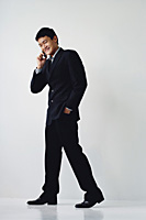 A man in a suit smiles as he talks on his cellphone - Asia Images Group