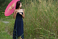 Woman in long grass with parasol - Asia Images Group