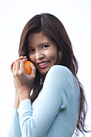 Woman holding orange, looking at camera - Asia Images Group