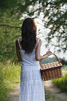 Woman with basket walking down country road - Asia Images Group