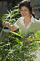 Woman watering plants in the garden - Asia Images Group
