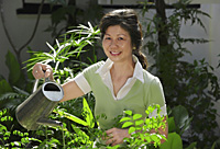 A woman watering plants in the garden - Asia Images Group