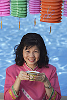 Woman drinking tea, surrounded by Chinese lanterns - Asia Images Group