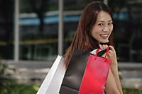 Woman with shopping bags, smiling over shoulder at camera - Asia Images Group