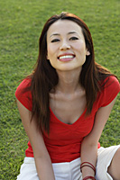 Woman sitting in park, smiling at camera - Asia Images Group