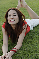 Woman lying in park, smiling at camera - Asia Images Group