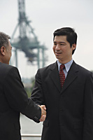 Businessmen standing face to face, shaking hands - Asia Images Group