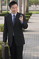 Businessman smiling while looking at mobile phone - Asia Images Group