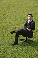 Businessman with quizzical expression sitting on office chair - Asia Images Group