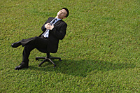 Businessman resting on an office chair - Asia Images Group