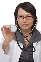 Doctor holding up stethoscope and looking at camera - Asia Images Group