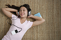 Young woman listening to music while lying down - Asia Images Group