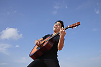 Man playing guitar outdoors - Asia Images Group
