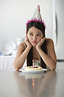 Young woman with birthday cake looking bored - Asia Images Group