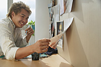 Man at desk smiling while looking at paper - Asia Images Group