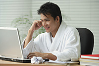 Man in bathrobe working at computer - Asia Images Group