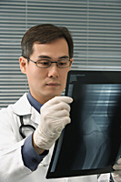 Doctor examining x-rays of knee - Asia Images Group